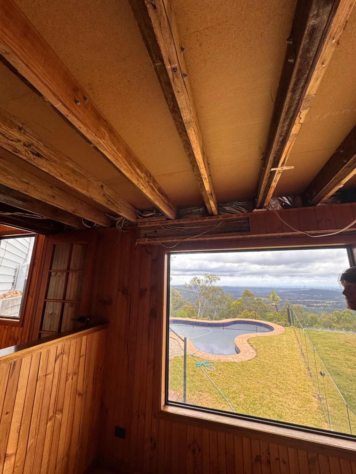 Exposed ceiling framing with damaged timber above a window