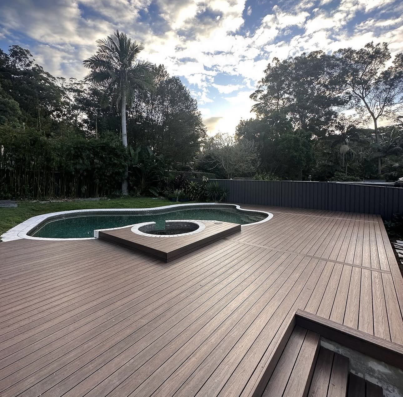 Large composite deck surrounding a backyard pool and spa