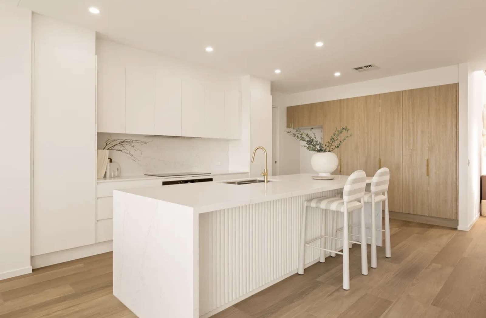 Modern white kitchen renovation with stone island bench, fluted detailing and timber joinery